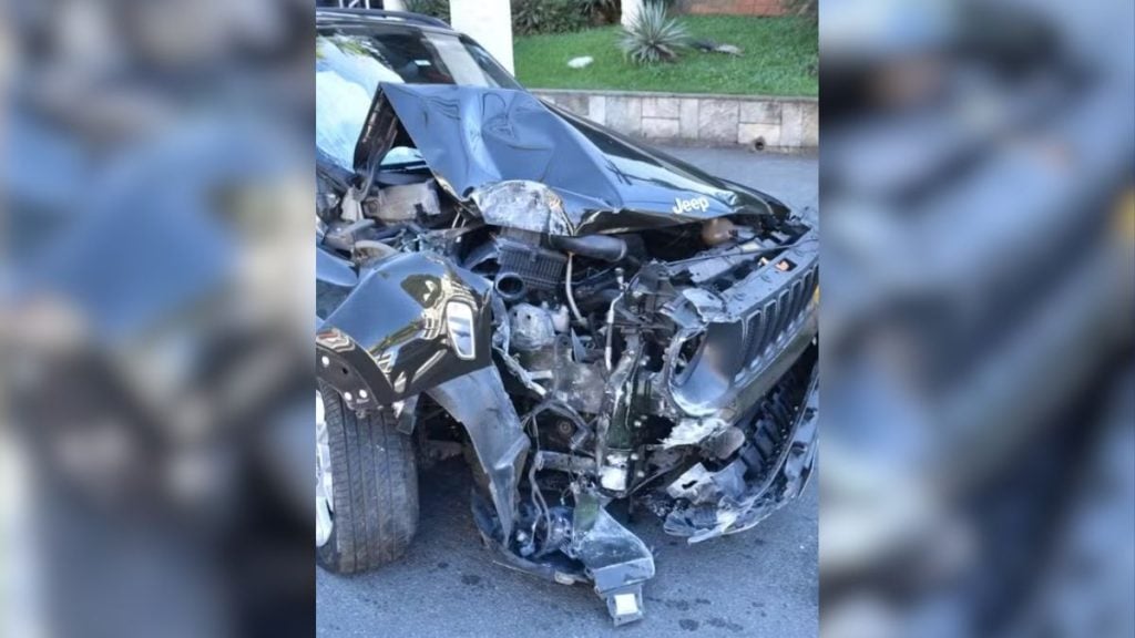 nutricionista morre em acidente no Guarujá: Carro com frente destruída após acidente, com parte da lataria e motor expostos ao lado da rua; imagem de reprodução relacionada à notícia sobre a Justiça após o caso no Guarujá.