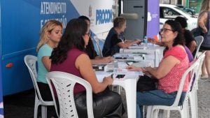 Atendimento do Procon Móvel em Santos em área externa, com equipe e moradores sentados em uma mesa durante o serviço ao público na quinta-feira.