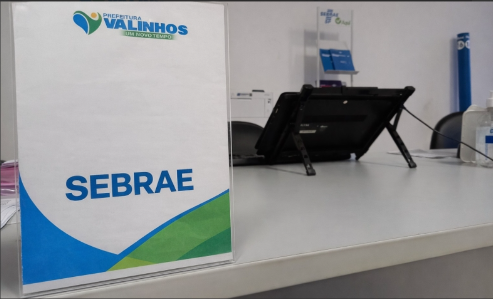 Painel do Sebrae na recepção de atendimento do Sebrae Aqui Valinhos em Valinhos, com computador e mesa ao fundo; imagem ilustrativa com sinalização do Sebrae