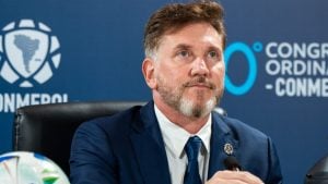 Presidente da Conmebol em coletiva de imprensa, defendendo a Copa do Mundo com 64 seleções em 2030, ao lado de microfone e brasão ao fundo