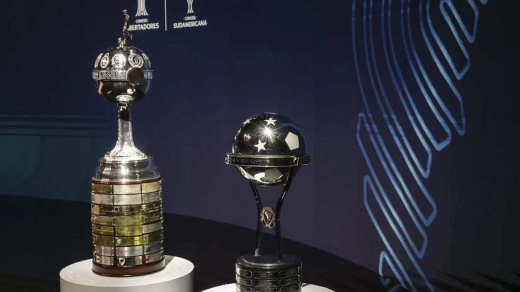 o que assistir após a Copa do Mundo: Taças da Libertadores e da Sul-Americana em destaque, com fundo azul e logotipos das competições ao lado das troféus em um cenário de premiação