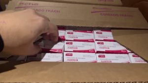 OperaÃ§Ã£o de combate ao roubo e ao desvio de medicamentos oncolÃ³gicos: caixas de remÃ©dios com rÃ³tulos visÃ­veis sendo manuseadas em uma investigaÃ§Ã£o, com mÃ£os ao lado do empilhamento.