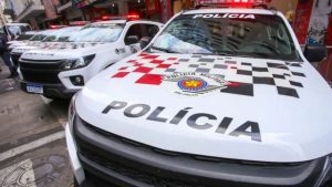 OperaÃ§Ã£o Janus: Viaturas da PolÃ­cia Militar na rua, com destaque para o emblema e a palavra âPOLICIAâ no capÃ´, em contexto de investigaÃ§Ã£o envolvendo PCC e coronÃ©is da PM de SÃ£o Paulo.