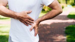 Hepatites virais: homem ao ar livre segurando a barriga em sinal de desconforto, ilustrando a importância da prevenção como vacina e higienização