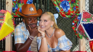 Virginia Fonseca e Vini Jr exibem sintonia em festa julina entre amigos, posando juntos com chapéu de cowboy e vestido claro em cenário decorado.