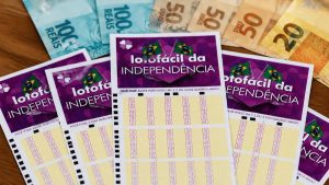 Lotofácil da Independência com cartões de apostas e números visíveis, em meio a outras cartelas de loteria, tema de sorteio com prêmio de R$ 300 milhões.