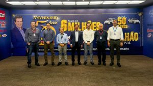 Foto de equipe em evento de comemoração dos 50 anos da Savegnago, com painel ao fundo anunciando mais de R$ 6 milhões em prêmios e campanha de aniversário.