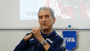 Parreira em coletiva de imprensa, com camisa azul da FIFA, falando diante de um telão e fundo com o logotipo FIFA, em foto jornalística.