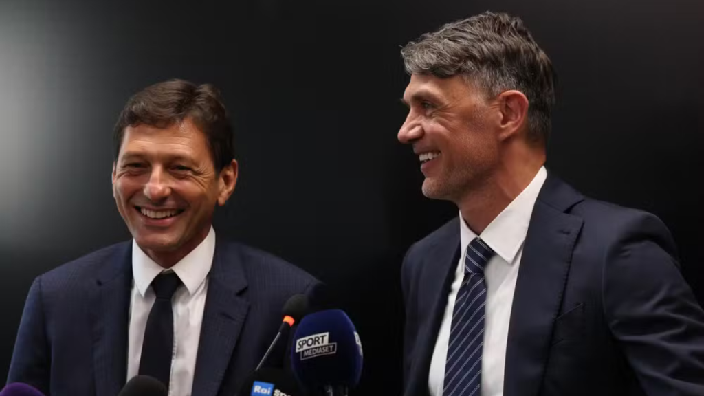 Ancelotti: Dirigentes da Federação Italiana de Futebol, Maldini e Leonardo, em foto oficial durante evento, sorrindo ao lado de microfones ao fundo. Foto Reprodução/FIGC.