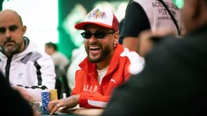 Neto Neymar: Neto detona Neymar em torneio de pôquer, com Neto sorrindo e conversando em volta das fichas e cartas na mesa, enquanto pessoas ao redor observam