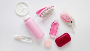 Imagem de cosméticos e itens de beleza sobre fundo branco, como escovas e frascos; alerta sobre cosméticos proibidos pela Anvisa, venda e uso de produtos irregulares.