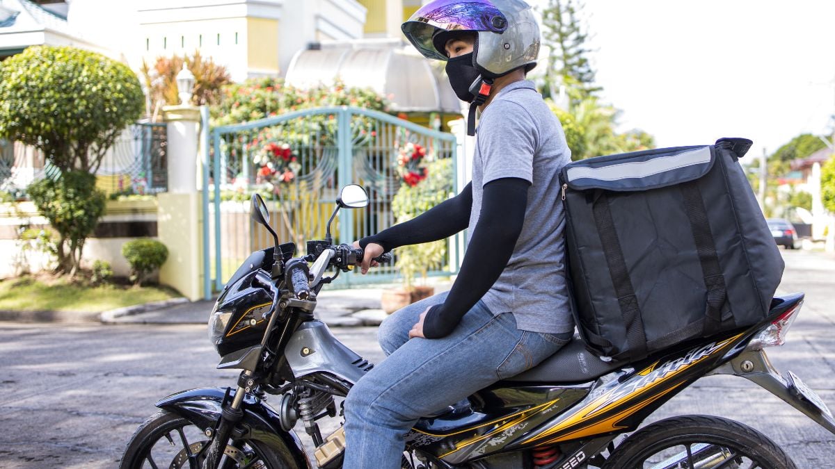 Entregador mototaxista em uma moto na rua, usando capacete e colete, com mochila de entregas, em cenário urbano. Move Brasil começa hoje: financiamento de motos sem entrada.