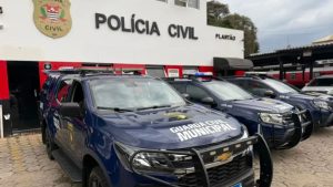 Viaturas da Polícia Civil em frente à unidade policial, com criança ao fundo em contexto de violência doméstica em Bragança Paulista envolvendo agressão contra mãe grávida