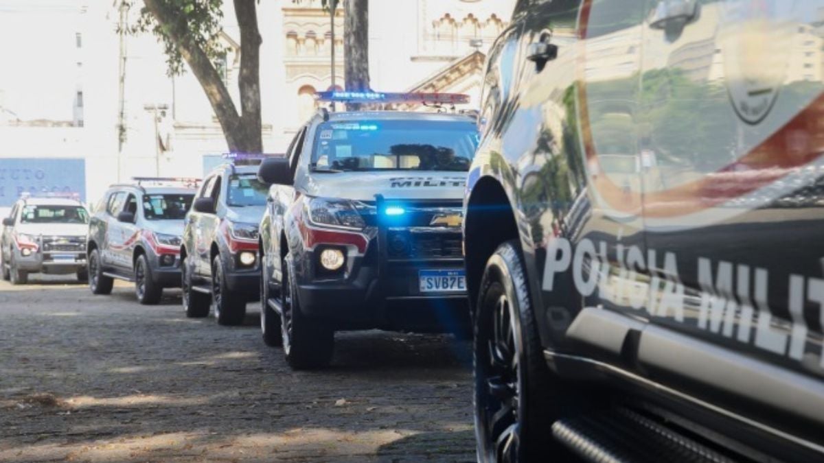 suspeito de manter o ex-sogro em cárcere privado: Viaturas policiais em fila na rua durante uma ocorrência em Mogi Guaçu, com foco em um carro da polícia com luzes azuis no patrulhamento.