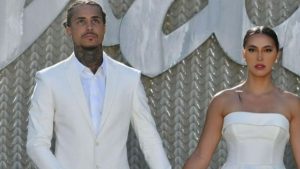 MC Livinho e influenciadora posam ao lado em foto formal, vestindo terno branco e vestido branco, com referência ao término do casamento após 10 anos de relacionamento.