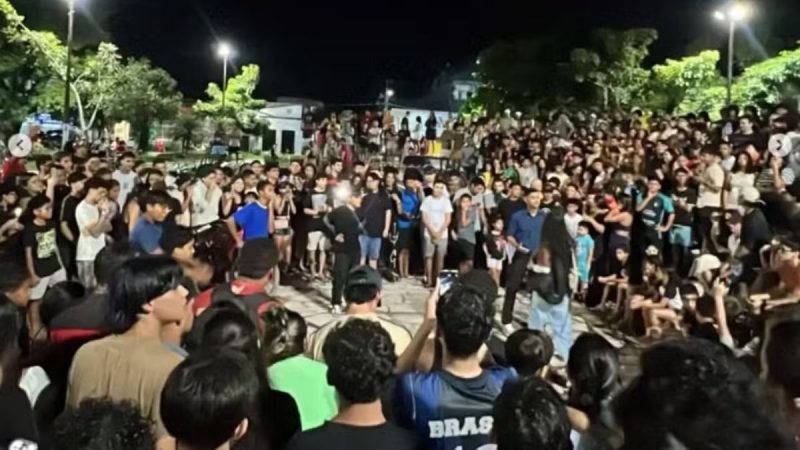 Prefeito veta campeonato farmar aura: Multidão reunida ao ar livre à noite em uma cidade do litoral de SP, em meio a um evento cercado por espectadores, com foco em reação popular e debate sobre a decisão do prefeito que veta campeonato de “farmar aura”.