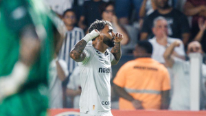 Gabigol em campo, vestindo a camisa do Santos, comemora um gol durante partida da Sul-Americana, enquanto torcedores ao fundo celebram a classificação às oitavas.