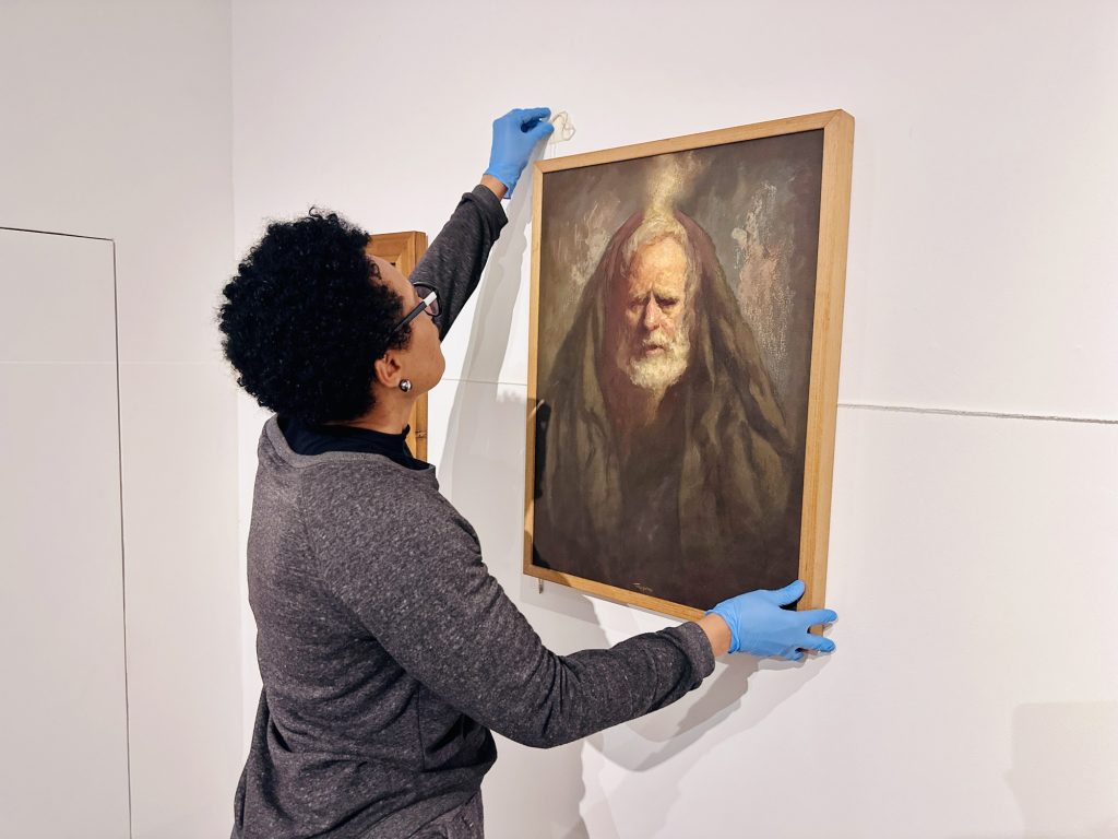Trabalhadora instala uma obra em moldura de madeira no salão de belas artes, na Pinacoteca Municipal, em preparação para o aniversário de Piracicaba