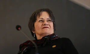Imagem de uma mulher palestrando em ambiente institucional, com foco no seu rosto, em referência à Lei Maria da Penha: a história que mudou o combate à violência contra a mulher no Brasil.