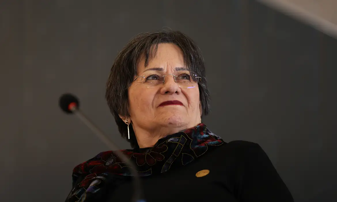 Imagem de uma mulher palestrando em ambiente institucional, com foco no seu rosto, em referência à Lei Maria da Penha: a história que mudou o combate à violência contra a mulher no Brasil.