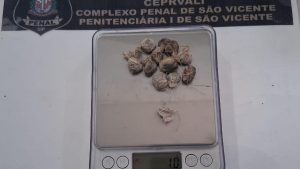 Imagem mostra um aparelho de escâner corporal com tela e visor, exibindo pequenos itens colocados em uma bandeja, durante inspeção de visitantes em presídios da Baixada Santista.