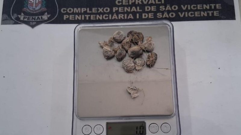 Imagem mostra um aparelho de escâner corporal com tela e visor, exibindo pequenos itens colocados em uma bandeja, durante inspeção de visitantes em presídios da Baixada Santista.