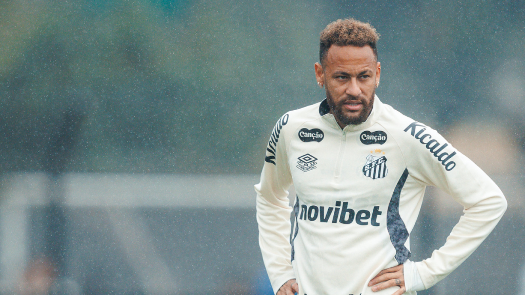Neymar durante treino do Santos, em foto de Raul Baretta para o Santos FC, usando uniforme branco com o escudo do clube e expressão focada.