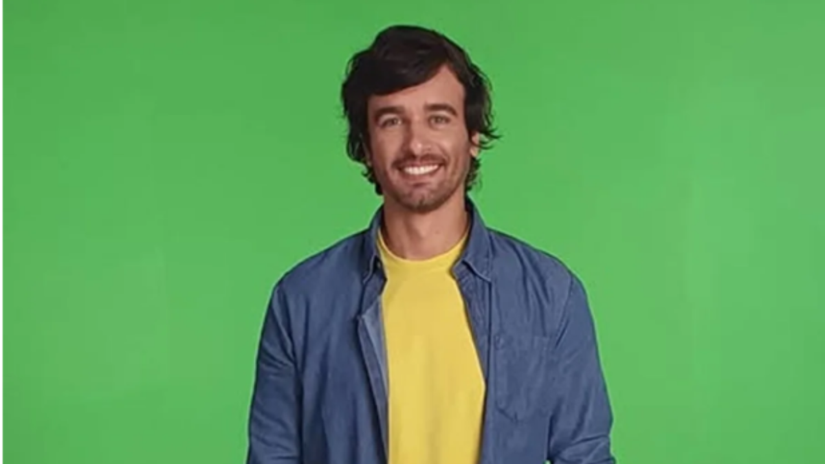 Marco Furlan aparece em imagem de estúdio, sorrindo e usando jaqueta azul sobre camiseta amarela, com fundo verde. Notícia relacionada ao caso.