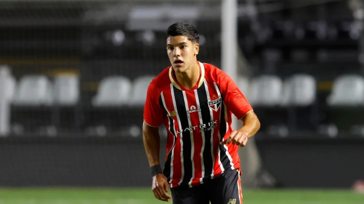 Nicolas, jogador do São Paulo, em campo durante partida, usando uniforme vermelho e preto com listras e expressão concentrada