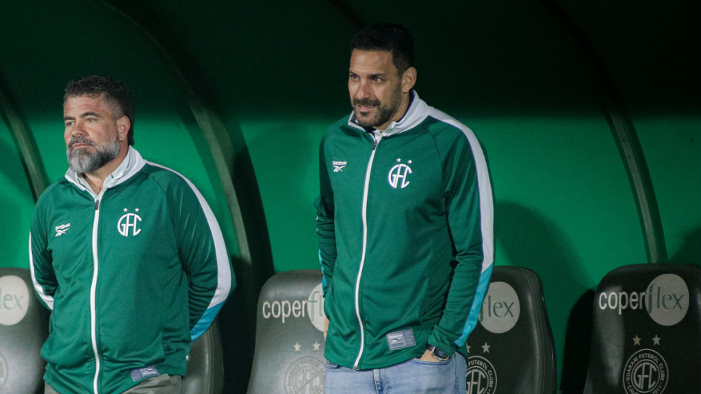 Rômulo Amaro, presidente do Conselho de Administração, ao lado do executivo de futebol Carlos Frontini no Guarani FC, em imagem com uniforme e ambiente de clube.