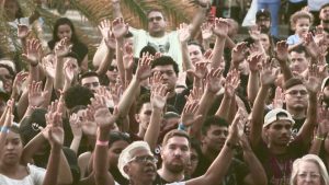 Festival Cultura Gospel em Campinas com FHOP Music, Nesk Only e 3 Palavrinhas: multidão em clima de culto e louvor, com pessoas erguidas e braços levantados ao ar em um evento ao ar livre