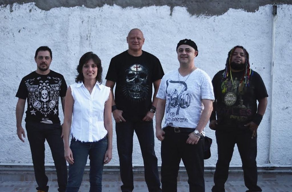 Integrantes da banda Ronaldo e Os Impedidos em foto de divulgação, com Ronaldo Giovanelli entre eles, em frente a um muro branco em ambiente externo. Festival Planeta Rock