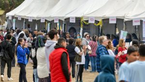 Movimentação de pessoas em tendas brancas durante a Feira Conexão Social em Campinas, com público reunido para projetos sociais e programação cultural ao ar livre.