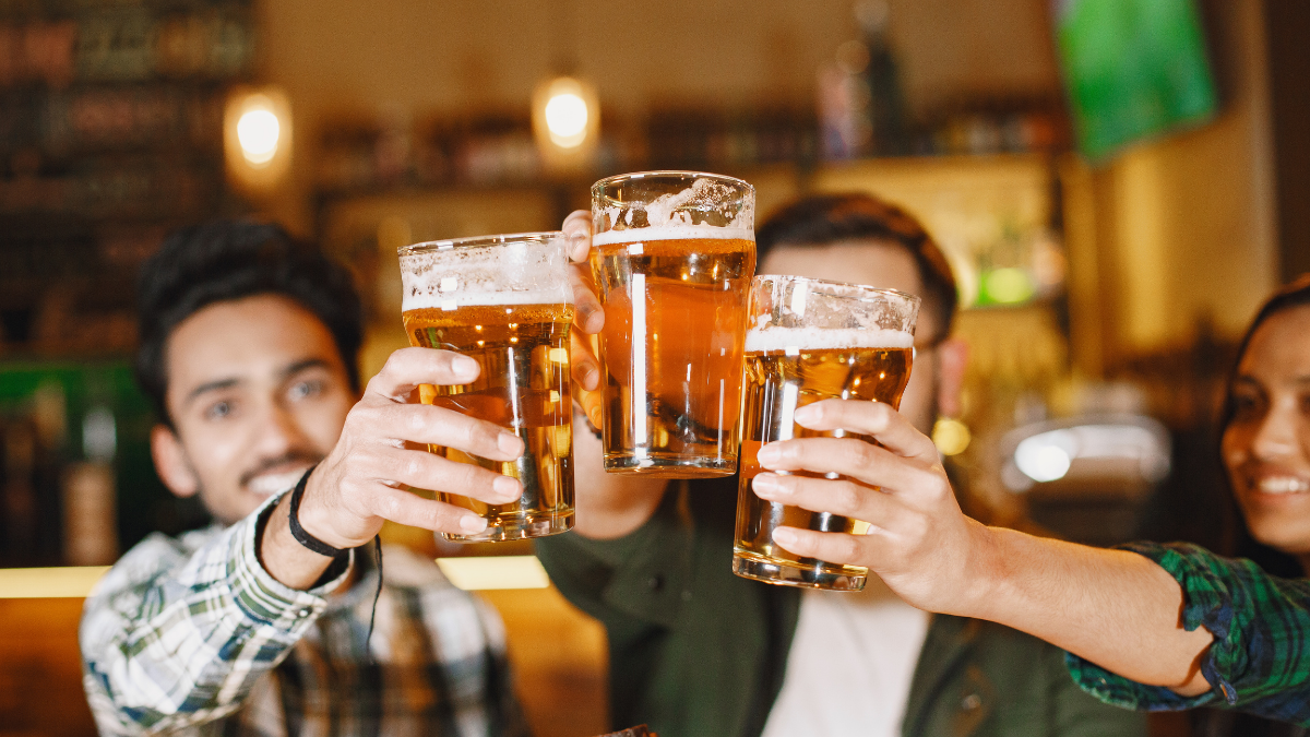 Dia Internacional da Cerveja: amigos brindando com copos de cerveja em uma cervejaria, em clima de comemoração.