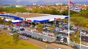 feirão de empregos Paulistão Atacadista: Vista aérea do Paulistão Atacadista em Indaiatuba, com estacionamento amplo e veículos, destacando 150 vagas para contratação imediata no feirão de empregos.