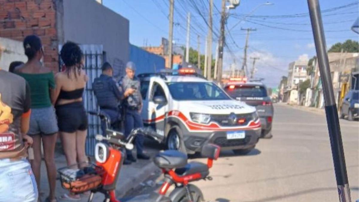 mulher encontrada morta em Campinas: Cena com viaturas da polícia na rua em Campinas após ocorrência de violência doméstica, com moradores ao lado de motocicletas e carros estacionados.