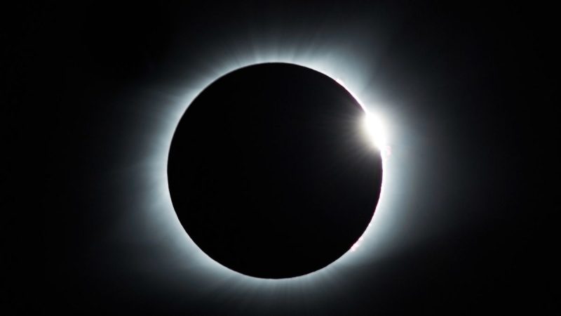 Eclipse solar em agosto, com o disco escuro da Lua cobrindo parcialmente o Sol e um halo luminoso ao redor no céu noturno.