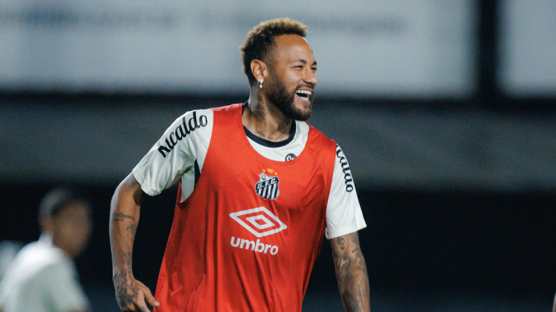 Neymar em treino pelo Inter Miami, sorrindo durante partida em que veste colete vermelho e uniforme branco, com cabelo curto e barba aparada