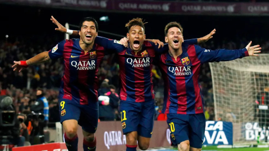 Neymar, Suárez e Messi comemoram juntos em campo pelo Barcelona, com os três jogadores do time catalão abraçados e braços abertos durante uma partida, foto de reprodução.