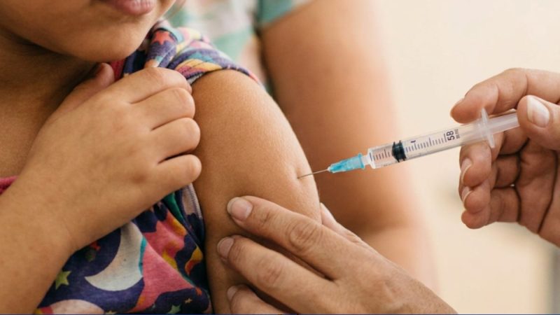 Vacinação em Atibaia: profissional aplica injeção na pele do braço de uma criança, durante atualização vacinal de crianças e adolescentes.