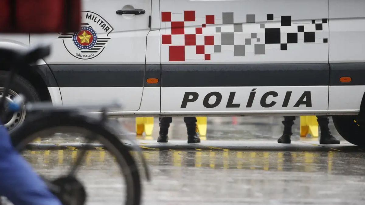 Homem sequestrado Guarujá: cena com viatura da polícia e agentes em frente a um supermercado, indicando o transporte do suspeito para realizar transferências bancárias.