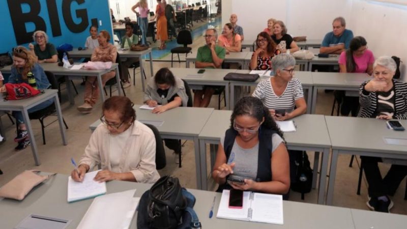inscrições para curso de tecnologia: Santos abre inscrições para curso gratuito de tecnologia para moradores 50+ com pessoas de diferentes idades fazendo atividades em sala de aula e estudando em mesas