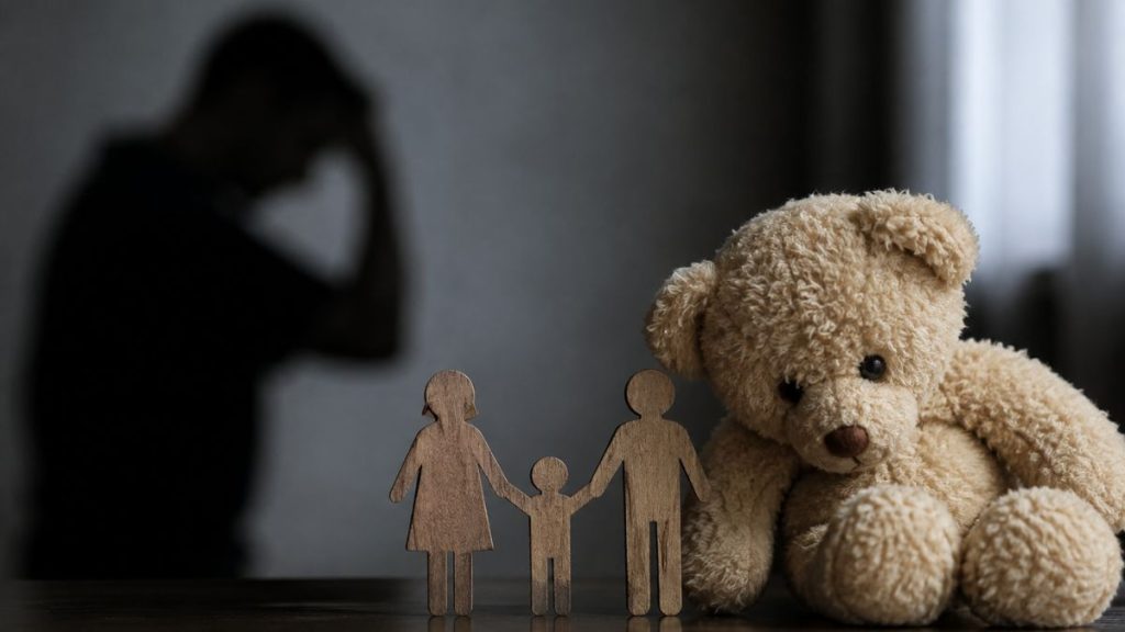 Cenário sombrio com um pai de silhueta ao fundo e brinquedo de pelúcia no primeiro plano, simbolizando luto e violência vicária em caso envolvendo pai e filhas após separação em SP.