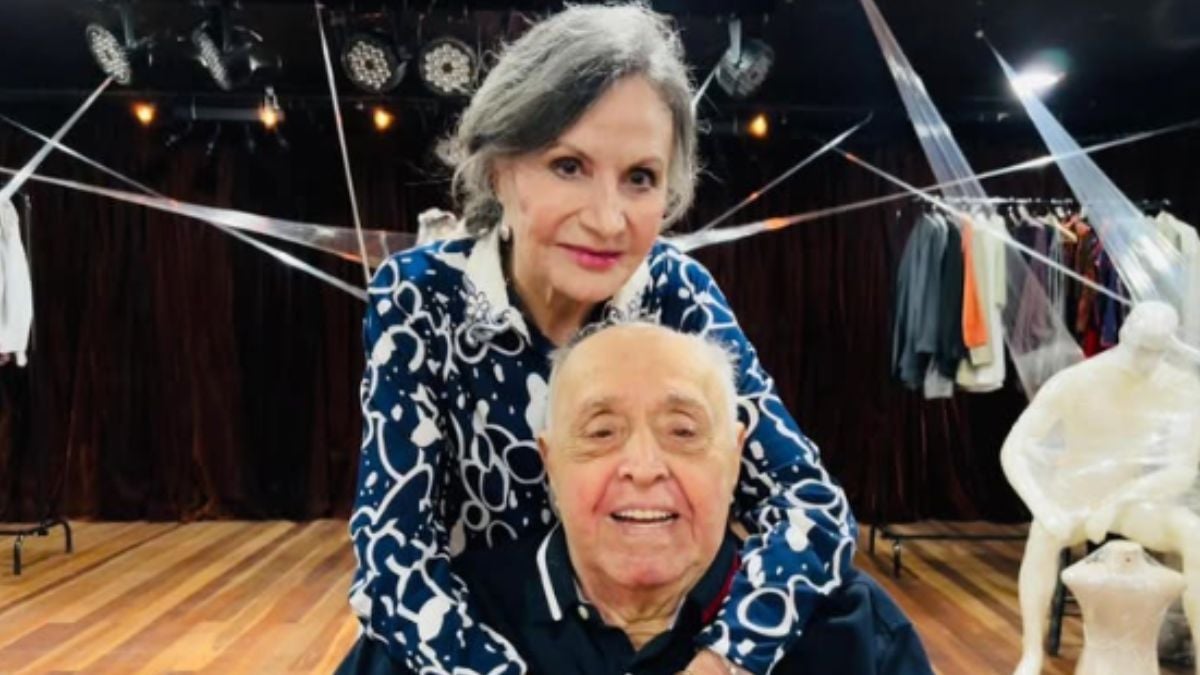 Rosamaria Murtinho ao lado de Mauro Mendonça, com ele sentado e sorridente, e ela abraçando durante atualização de saúde de Mauro Mendonça após foto no Dia dos Pais.