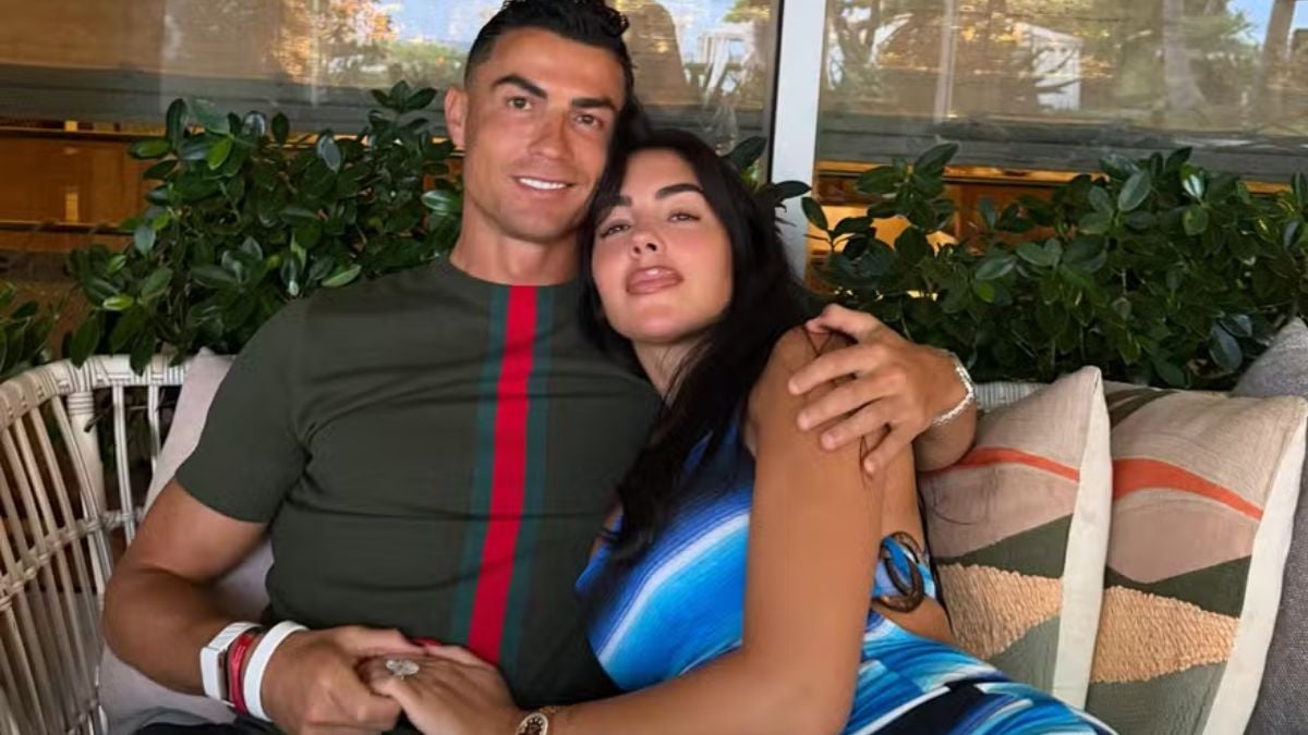 Cristiano Ronaldo ao lado de Georgina Rodríguez em foto romântica, sentados em um ambiente interno com plantas ao fundo, celebrando o casamento após 10 anos juntos.