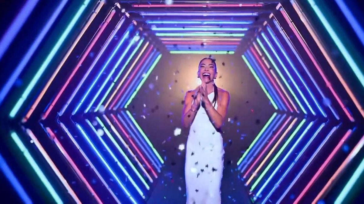 SBT 45 anos com vinheta especial: apresentadora em palco ao centro, cercada por luzes neon e efeitos gráficos coloridos, celebrando aniversário da emissora.
