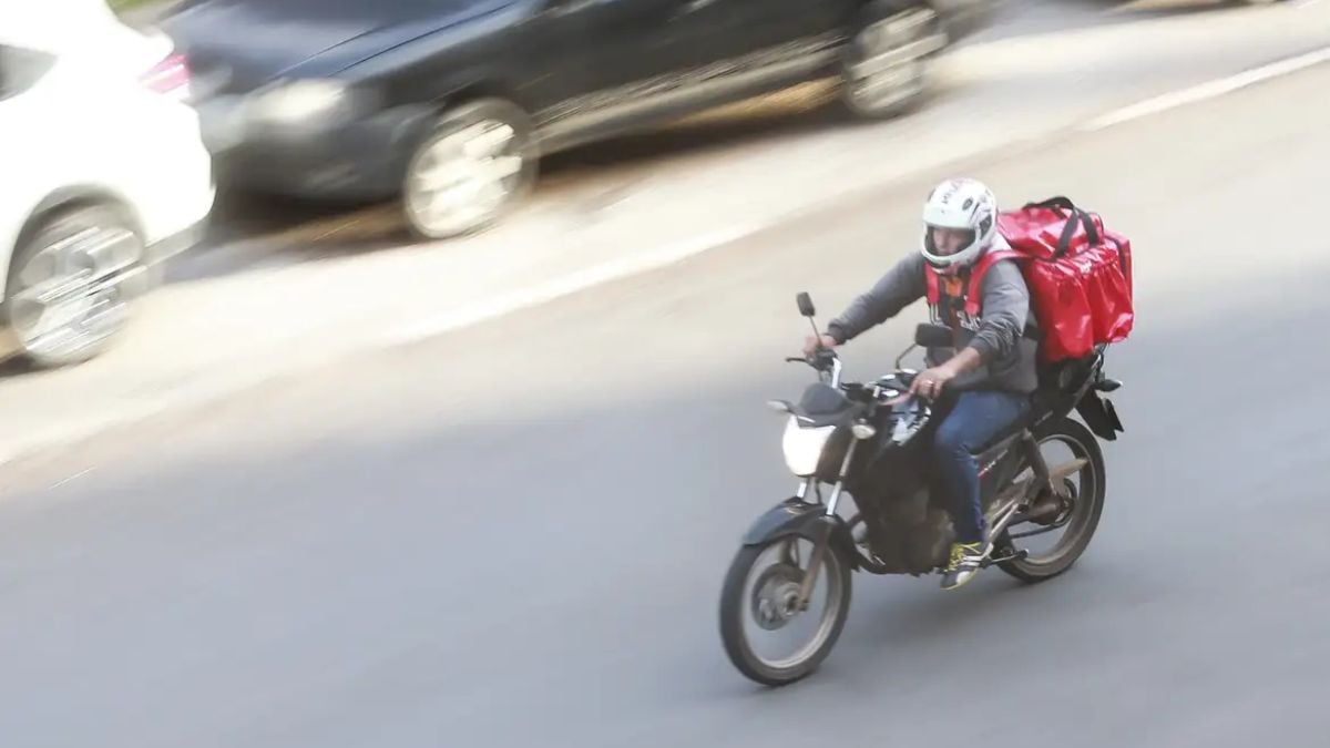 Motoboy em uma motocicleta na rua, com mochila de entrega, ilustrando o Projeto para entregadores em Itanhaém sobre criação de pontos de descanso para trabalhadores