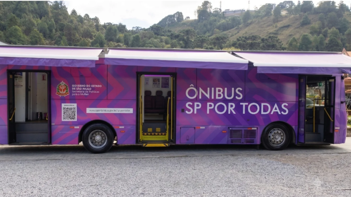 Ônibus SP Por Todas em Amparo com atendimento gratuito às mulheres, veículo roxo e magenta com identificação “ÔNIBUS SP POR TODAS” estacionado em área externa.