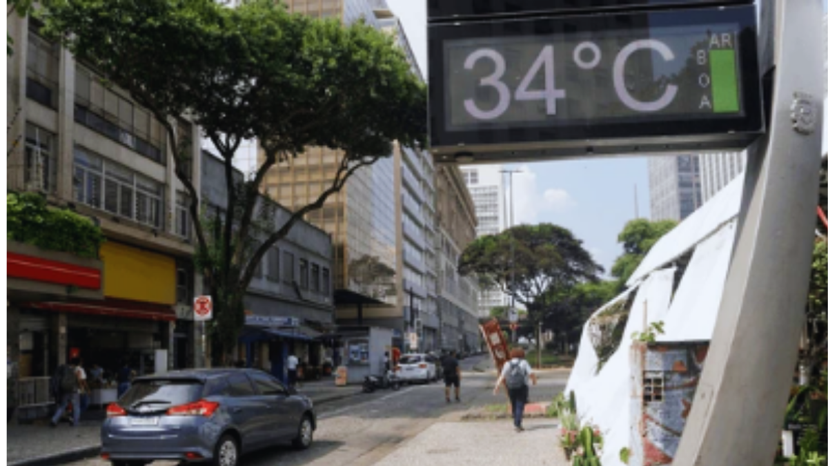 Onda de calor em SP: Defesa Civil alerta com termômetro marcando 34°C em avenida com prédios e árvores, indicando regiões afetadas.