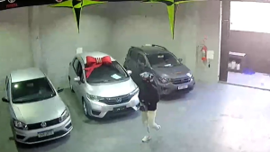 loja de veículos assaltada em Hortolândia: Câmeras de segurança mostram uma loja com carros estacionados em um ambiente fechado, enquanto criminosos armados fazem um assalto em Hortolândia e trancam funcionário no banheiro.